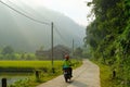 Ba Be Lakes / Vietnam, 04/11/2017: Motorbiking backpacker passing rice paddies and local houses on a road during sunrise in the