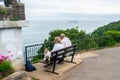 BABBACOMBE, TORQUAY, ENGLAND- 26 June 2021: Man and woman sitting on a bench with a dog