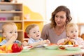 Babies and carer together eat fruits and vegetables as a snack in the kindergarten, nursery or daycare Royalty Free Stock Photo