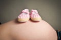 Babies first shoes resting on a pregnancy bump