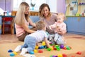 Babies play and their mothers communicate in playroom Royalty Free Stock Photo