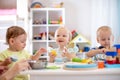 Babies playing together in the kindergarten or creche. Kids sitting at table in nursery or daycare