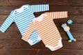 Babies striped bodysuits, toy and pacifier on wooden background. Royalty Free Stock Photo