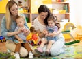 Babies toddlers playing with colorful educational toys together with mothers in nursery room Royalty Free Stock Photo