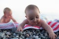 Babies touching pebble on the beach. Exploring the world by playing