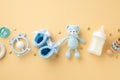 Baby accessories concept. Top view photo of blue knitted booties teddy-bear toy milk bottle teether wooden rattle pacifier and Royalty Free Stock Photo