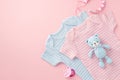 Baby accessories concept. Top view photo of pink and blue bodysuits baby`s dummy chain and knitted teddy-bear toy on isolated Royalty Free Stock Photo