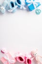 Top view vertical photo of pink and blue knitted booties gift boxes teddy bear toys and pacifiers on white background Royalty Free Stock Photo