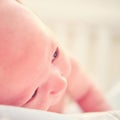 A baby aged 1 month learns to keep his head lying on his stomach. Caucasian boy child in a home white bedroom