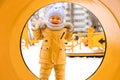 A baby aged 12-17 months , looks into a yellow pipe on the playground in winter Royalty Free Stock Photo