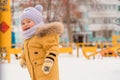 A baby aged 12-17 months, runs on the playground in winter