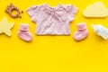 Baby background. Clothes, booties and accessories for newborn girl on yellow table top-down frame copy space Royalty Free Stock Photo