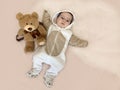 Baby and bear. A beautiful smiling toddler lies on the bed next to his favorite soft toy. Royalty Free Stock Photo