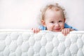 Baby on the bed mattress close-up. The sidewall of the mastras is stitched with finishing lines. Royalty Free Stock Photo