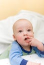 Baby on bed put fingers in mouth Royalty Free Stock Photo