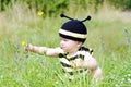 Baby in bee costume reaches for a flower