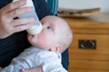 a baby being fed a bottle while on the chest of a person