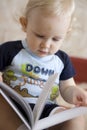 Baby blond boy with book indoors