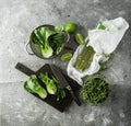 Baby bok choi halves, uncooked green tea noodles, limes, green sprouts on gray background. Top view, square image