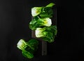 Baby bok choi halves on black background. Top view, horizontal orientation