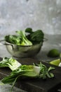 Baby bok choi halves on black cutting board on gray background. Vertical image