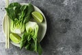 Baby bok choi halves, limes, chopsticks on gray background. Top view, horizontal orientation with copy space