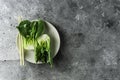 Baby bok choi halves on a plate gray background. Top view, horizontal orientation with copy space