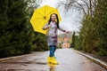 Baby Boomers Happy senior woman in yellow rain coat with yellow umbrella jumping and enjoying life in park. Royalty Free Stock Photo