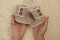 Baby booties for newborn baby in mother hands, pregnant girl with hand knetted baby shoes expecting baby. pregnancy concept.