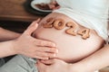 Baby born in 2024. Cropped photo of pregnant woman holding number 2024 of ginger cookies on belly.