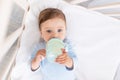 Baby with a bottle of milk in his hands in the crib eating, baby food concept Royalty Free Stock Photo