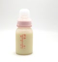 Baby bottle with milk and a measuring scale on the background of a lot of full bottles of breast milk.