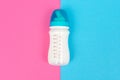 Baby bottle of white milk on pink blue table background Royalty Free Stock Photo