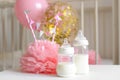 Baby bottles with breast milk with various festive paper decor and balloons in front of baby bedroom. It`s a girl or baby birthda Royalty Free Stock Photo