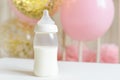 Baby bottles with breast milk with various festive paper decor and balloons in front of baby bedroom. It`s a girl or baby birthda Royalty Free Stock Photo