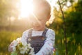 Baby with bouquet of flowers in the garden in sunlight. Cute happy summer blond girl in the garden. Apple blossom Royalty Free Stock Photo