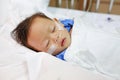 Baby boy age about 1 year old sleeping on patient bed with getting oxygen via nasal prongs to assure oxygen saturation. Intensive Royalty Free Stock Photo