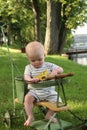 Baby boy in antique stroller near water in backyard