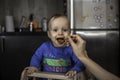 Baby boy being fed by mother in kitchen Royalty Free Stock Photo