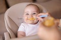 Baby boy being fed with porridge while sitting in high chair Royalty Free Stock Photo