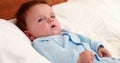 Baby boy in blue babygro lying on bed