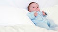 Baby boy in blue babygro lying on pillows