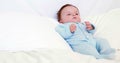 Baby boy in blue babygro lying on pillows