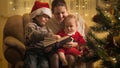 Baby boy with brother and mother reading fairy tale book on Christmas eve . Families and children celebrating winter Royalty Free Stock Photo
