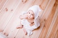 Baby boy with brown eyes is five months old wrapped in a white towel with ears on wooden background . Royalty Free Stock Photo