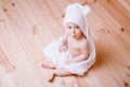 Baby boy with brown eyes is five months old wrapped in a white towel with ears on wooden background . Royalty Free Stock Photo
