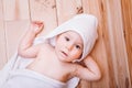 Baby boy with brown eyes is five months old wrapped in a white towel with ears on wooden background . Royalty Free Stock Photo