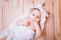 Baby boy with brown eyes is five months old wrapped in a white towel with ears on wooden background . Royalty Free Stock Photo