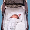 Baby boy in a carriage on a blue background. A child in white clothes in only diapers is lying in a stroller, studio shot Royalty Free Stock Photo