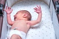 Baby boy in a carriage on a blue background. A naked child in only diapers is lying in a stroller, studio shot